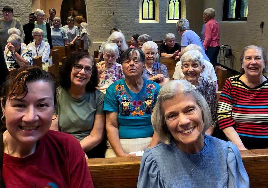 Group photo of smiling Loretto Community members gathering in the pews of the Loretto Motherhouse church.