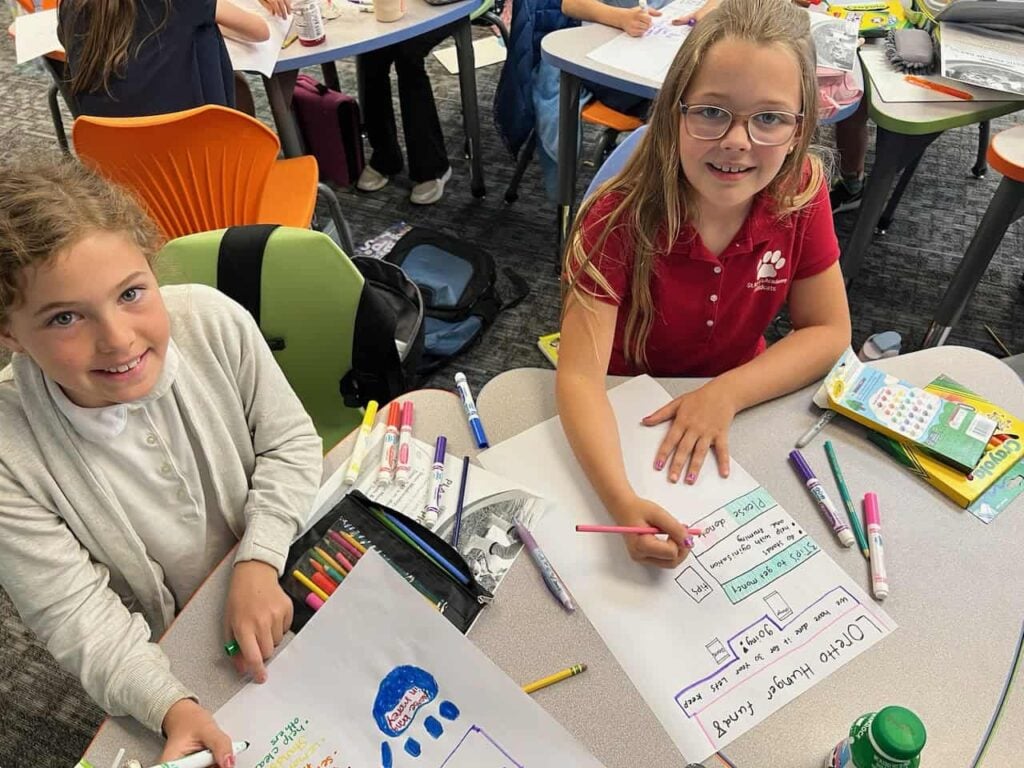 Two elementary aged girls create handmade posters about the Loretto Hunger Fund.