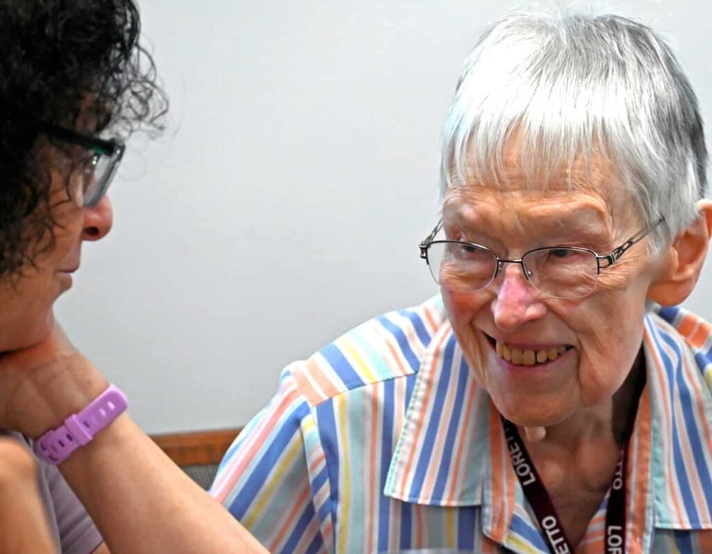 Two women smiling and laughing together at a gathering.