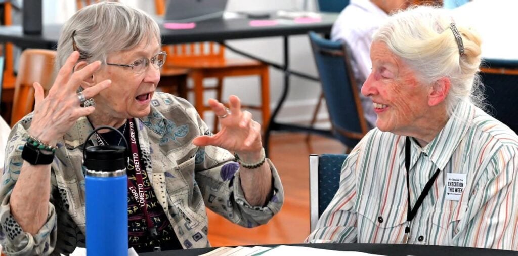 Two older women in their late 80s having a lively discussion at a gathering.