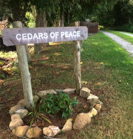 A carved wooden road sign reads "Cedars of Peace"