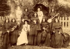 A black and white photo from the 1880s of St. Mary's teachers in full habits and friends enjoying the outdoors. One woman is carrying a banjo and another a guitar.