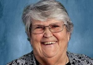 An older gray haired woman in professional attire smiles