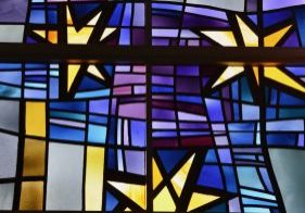 A stained glass window shines with golden stars and a blue and purple background