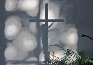 Shadow of a crucifix on a white-painted brick wall.
