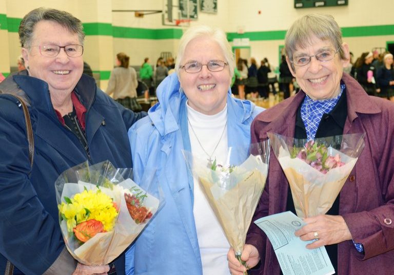 Donna Day SL, Annie Stevens SL and Barbara Ann Barbato stand smiling and holding bouquets of flowers.