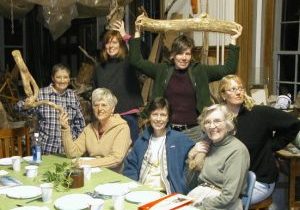Seven women gather for a lighthearted photo at a dinner table in Jeanne Dueber's art studio.