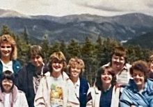 A blurry older photo of a group of adults and kids in front of Colorado mountains smiling for a photo on a hike.