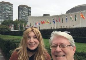 Two women smile in a selfie, with the flags of nations in the background.