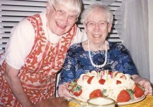Cecily Jones SL and Mary Luke Tobin SL smile while posed with a strawberry birthday cake.