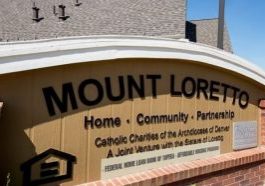 Sign outside building reads "Mount Loretto: Home. Community. Partnership" Subheading: Catholic Charities of the Archdiocese of Denver. A Joint Venture with the Sisters of Loretto.