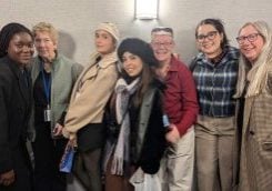 A group of women of diverse ages and backgrounds pose for a quirky group photo.