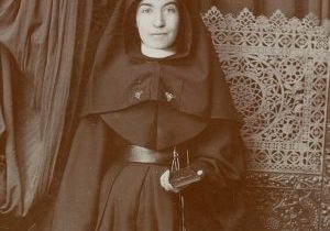 Archival formal photo of a young Sister Lucia Perea in habit holding her bible and posing.