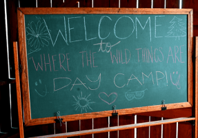 A chalkboard that says "Welcome to where the wild things are day camp"