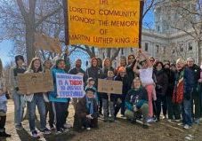 A large group of individuals collected outdoors for a photo with a sign saying, "Loretto Community honors the memory of Martin Luther King Jr.