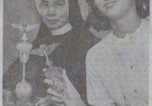 A historical newspaper photo of a nun in habit and a woman in glasses each holding the same standard.