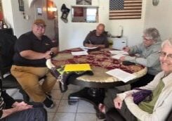 Three women and two men are sitting at a round table signing a lease.