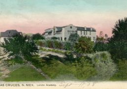 Historic postcard showing a white, southwest-style building with low trees and shrubs surrounding in and in the foreground. Printed text on the bottom reads "Las Cruces, N. Mex. Loretto Academy" The date "Sept 11, [19]08" is handwritten.