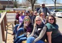A group of teachers sitting on a farm hayride on a sunny day.